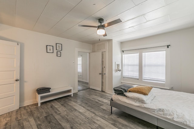 bedroom featuring baseboards, wood finished floors, a ceiling fan, and ornamental molding