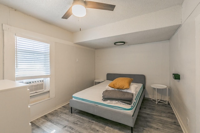 bedroom featuring cooling unit, baseboards, a textured ceiling, and wood finished floors