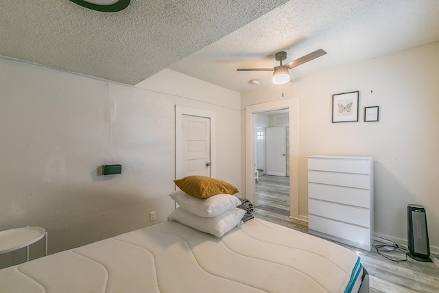 bedroom featuring a ceiling fan, wood finished floors, and a textured ceiling