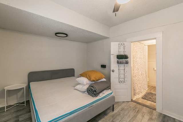 bedroom with baseboards, ceiling fan, wood finished floors, a textured ceiling, and ensuite bath