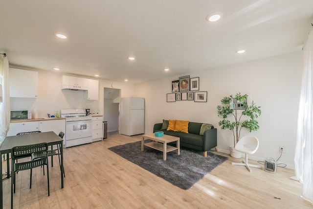 living area with recessed lighting, light wood-type flooring, and baseboards