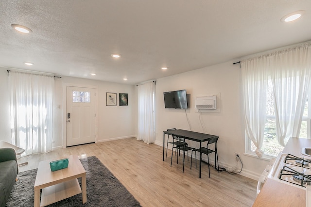 living room with recessed lighting, baseboards, light wood-style floors, and a wall mounted air conditioner
