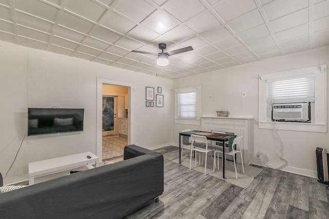 living room featuring cooling unit, baseboards, a ceiling fan, and wood finished floors