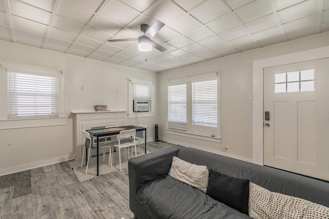 living area featuring cooling unit, wood finished floors, baseboards, and ceiling fan