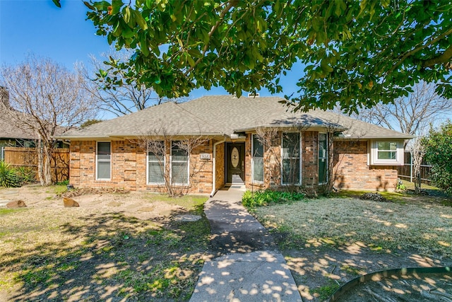 single story home featuring fence, brick siding, and roof with shingles