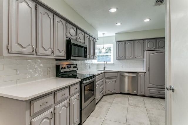 kitchen featuring light tile patterned floors, visible vents, gray cabinets, a sink, and stainless steel appliances