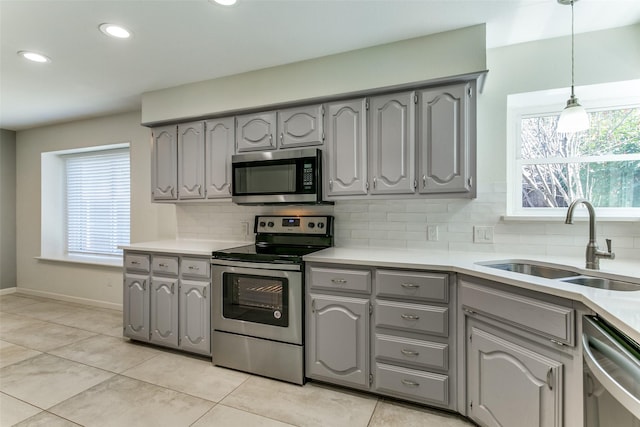 kitchen with gray cabinetry, a sink, tasteful backsplash, appliances with stainless steel finishes, and light countertops