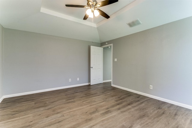 spare room with ceiling fan, a raised ceiling, baseboards, and wood finished floors