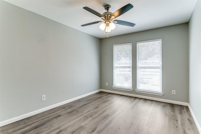 empty room with baseboards, a healthy amount of sunlight, and wood finished floors