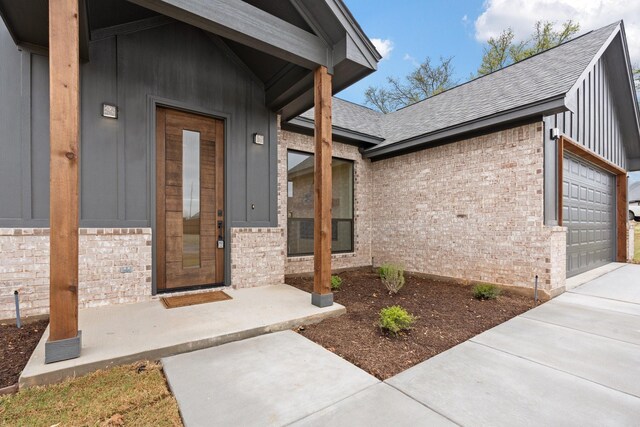 3306 Promenade Ct, Granbury, TX 76049 - doorway to property with brick siding, an attached garage, a shingled roof, concrete driveway, and board and batten siding