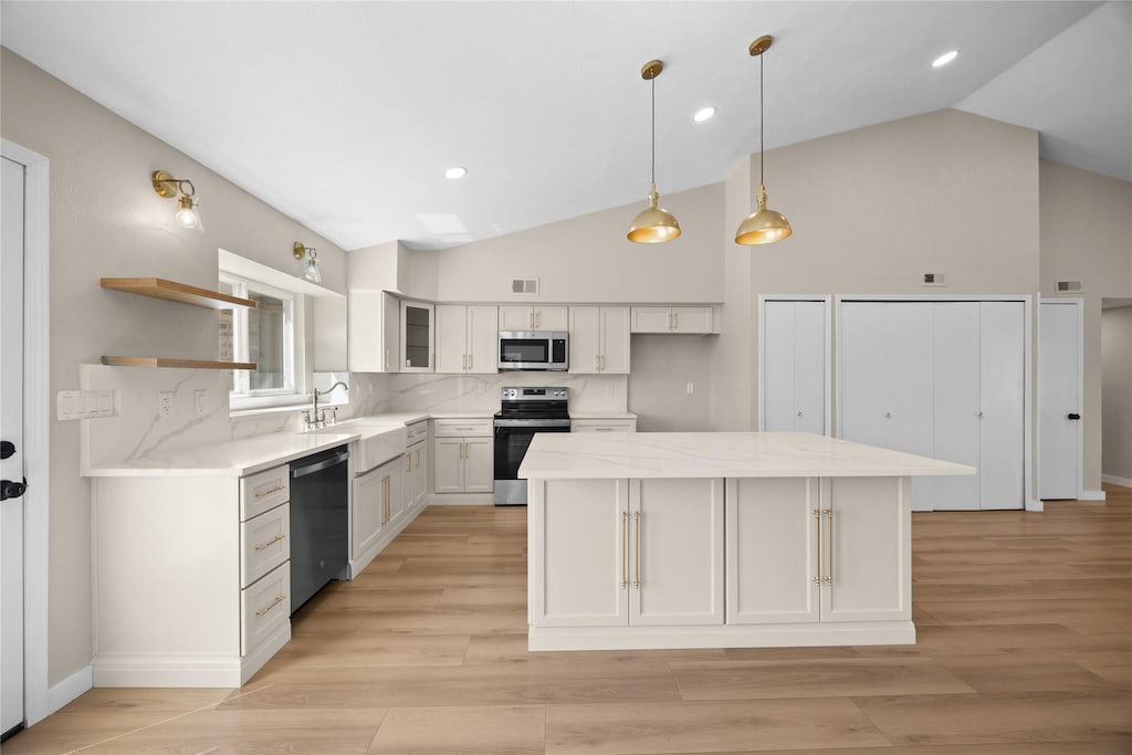 2933 Kingswood Dr, Garland, TX 75040 - kitchen featuring stainless steel appliances, vaulted ceiling, white cabinets, a kitchen island, and light stone counters