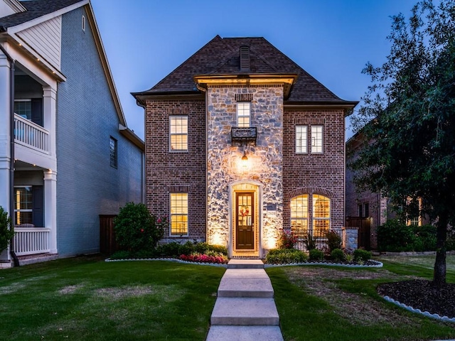 french country style house with a front yard and brick siding