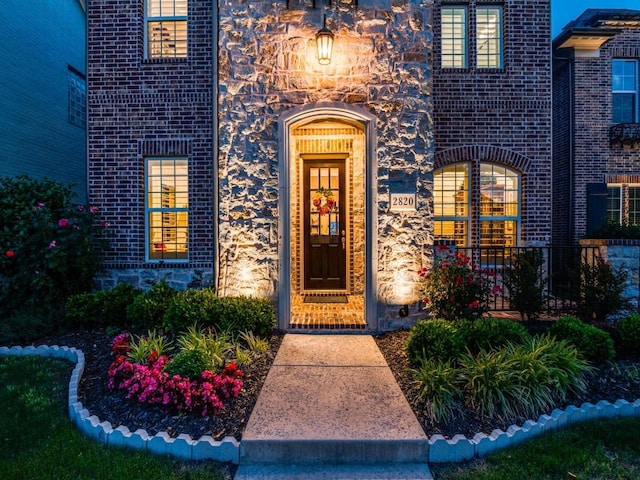 entrance to property featuring brick siding and stone siding