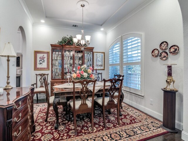 dining room with a notable chandelier, visible vents, crown molding, and baseboards