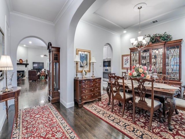 dining room with arched walkways, dark wood-style floors, and ornamental molding