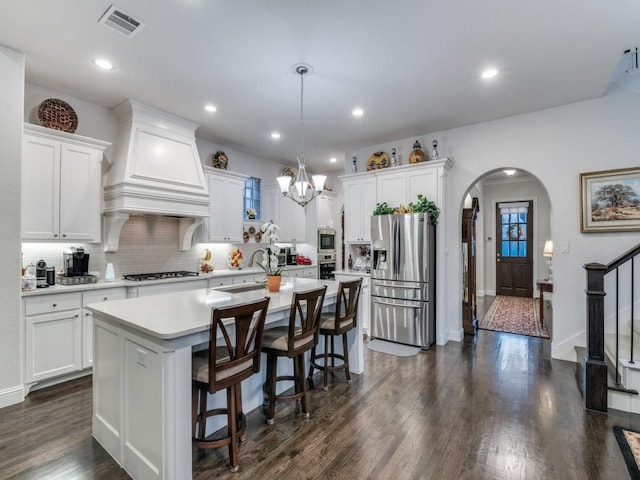 kitchen featuring visible vents, light countertops, arched walkways, stainless steel appliances, and a sink