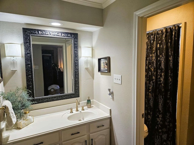 bathroom with toilet, vanity, crown molding, and a textured wall