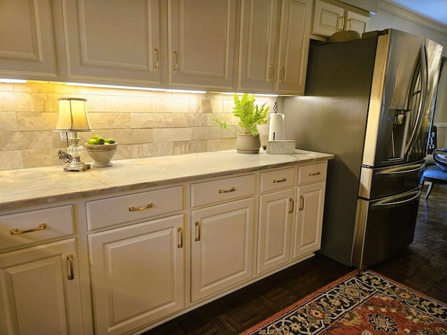 kitchen with tasteful backsplash, stainless steel fridge, white cabinets, and light stone countertops