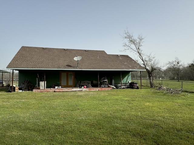 rear view of property with a patio, fence, a shingled roof, and a yard