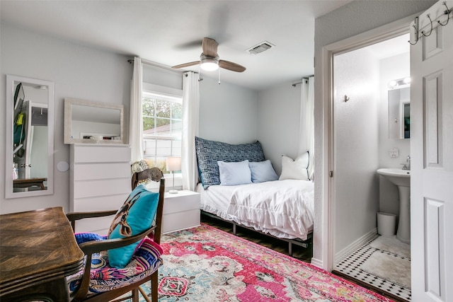 bedroom with baseboards, visible vents, a sink, ceiling fan, and ensuite bathroom