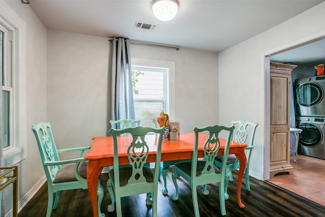 dining space featuring visible vents, stacked washing maching and dryer, and baseboards