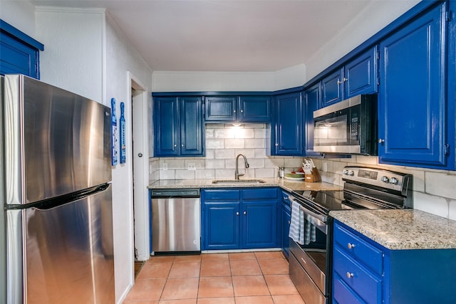 kitchen featuring light tile patterned floors, blue cabinetry, a sink, decorative backsplash, and appliances with stainless steel finishes