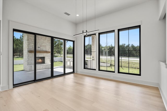 unfurnished room with visible vents, baseboards, a stone fireplace, light wood-type flooring, and recessed lighting