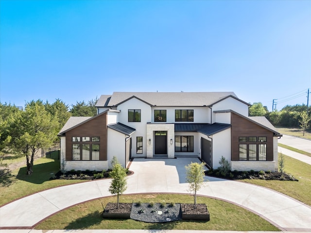 view of front facade featuring curved driveway, stone siding, a front lawn, a standing seam roof, and metal roof