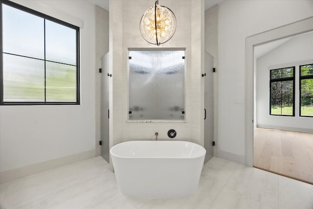 full bathroom featuring a chandelier, a soaking tub, baseboards, and a shower stall