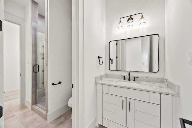 full bath featuring toilet, a shower stall, vanity, and baseboards