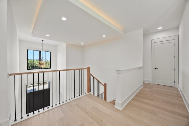 hall featuring recessed lighting, a chandelier, wood finished floors, an upstairs landing, and baseboards