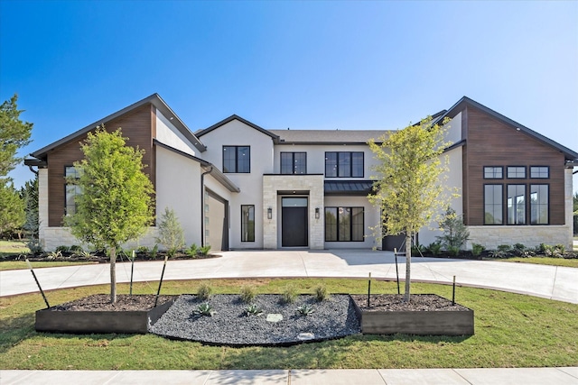 view of front of home featuring a front yard, driveway, stone siding, and stucco siding