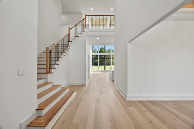 foyer featuring wood finished floors, a high ceiling, baseboards, and stairway
