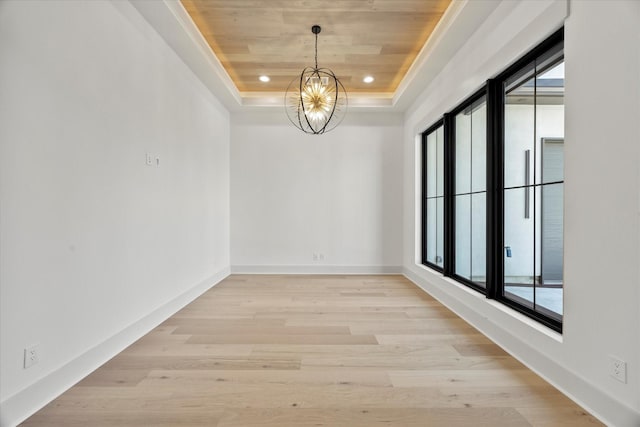 unfurnished room featuring light wood-style floors, recessed lighting, wooden ceiling, a raised ceiling, and a notable chandelier