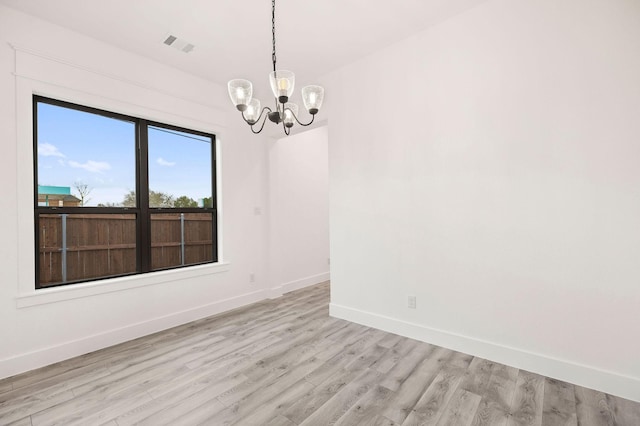 unfurnished room featuring visible vents, baseboards, light wood-type flooring, and an inviting chandelier