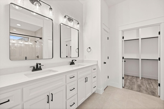 bathroom featuring a sink, double vanity, a shower stall, and tile patterned flooring