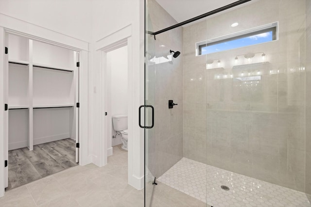 bathroom with a shower stall, a spacious closet, and toilet