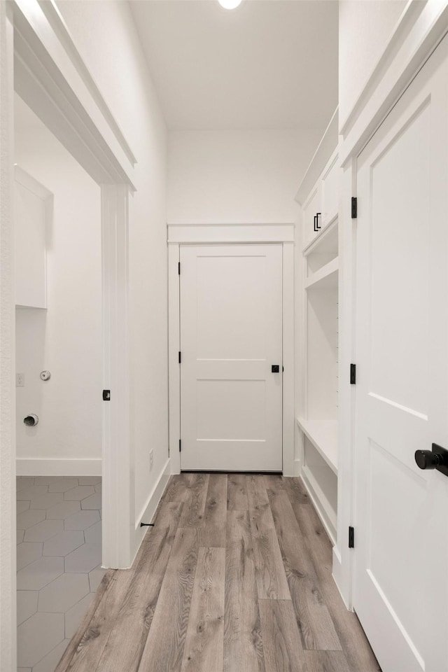hall with light wood-style flooring and baseboards