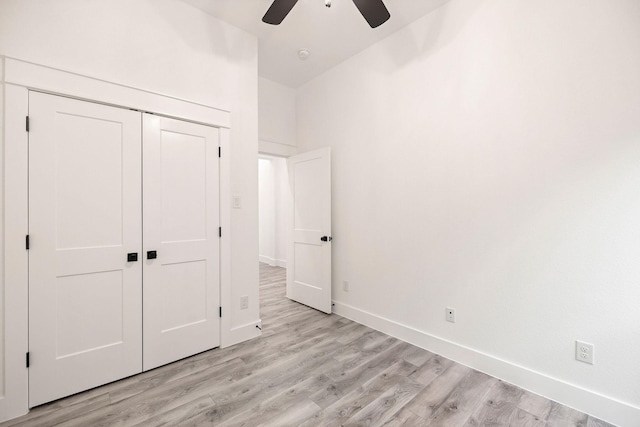 unfurnished bedroom with lofted ceiling, light wood-style flooring, a ceiling fan, a closet, and baseboards