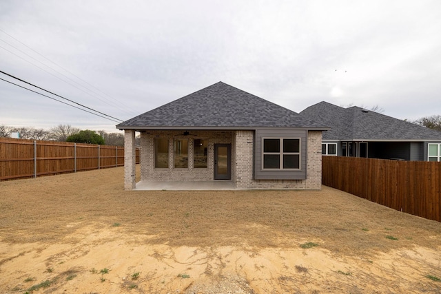rear view of house featuring a patio, a fenced backyard, brick siding, and roof with shingles