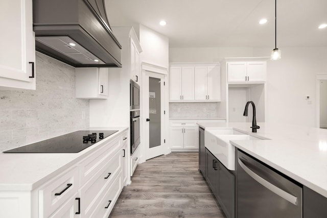 kitchen featuring premium range hood, light countertops, appliances with stainless steel finishes, white cabinets, and a sink