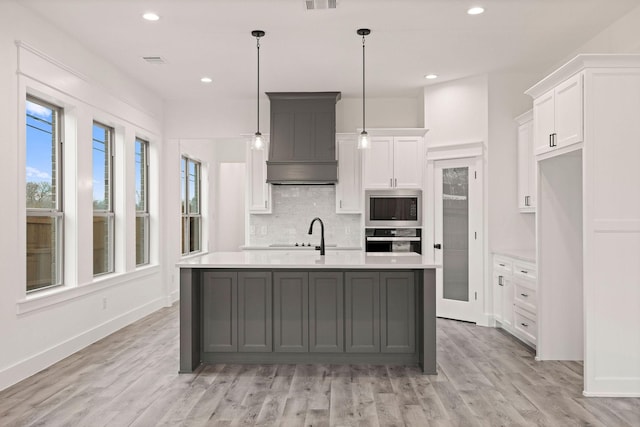 kitchen featuring premium range hood, built in microwave, light countertops, stainless steel oven, and tasteful backsplash