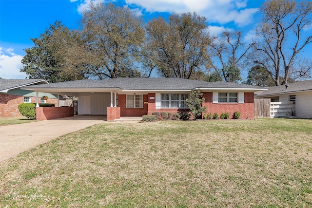 single story home featuring brick siding, an attached carport, fence, a front yard, and driveway