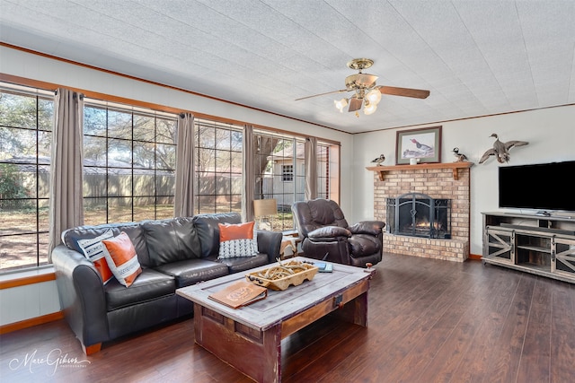 living area with a wealth of natural light, a fireplace, a ceiling fan, and hardwood / wood-style flooring