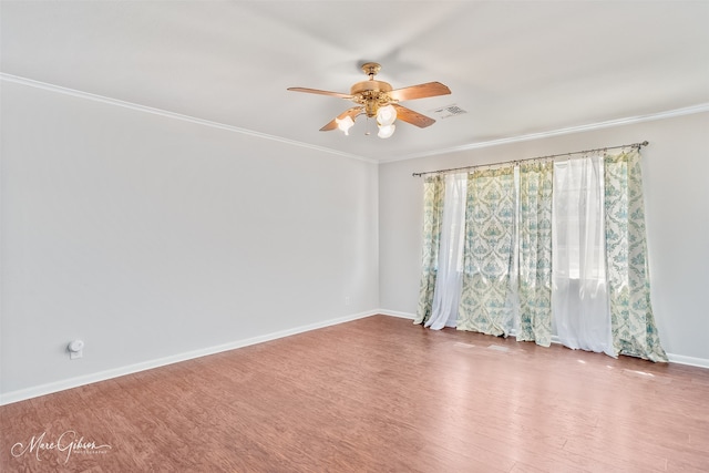 spare room with wood finished floors, visible vents, baseboards, ceiling fan, and crown molding