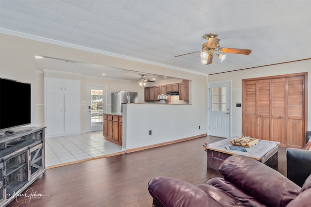 living area featuring crown molding, a ceiling fan, and light wood-style floors