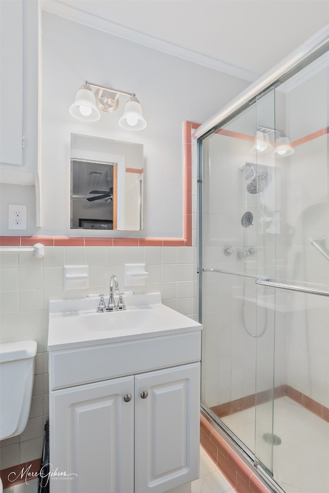 bathroom with vanity, a stall shower, ornamental molding, tile walls, and toilet