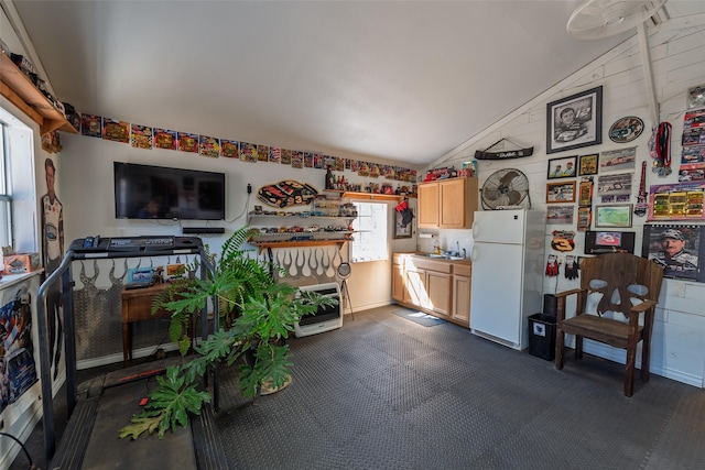 kitchen featuring light brown cabinets, a sink, heating unit, freestanding refrigerator, and lofted ceiling