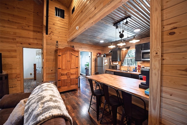 dining area featuring dark wood finished floors, wooden ceiling, wooden walls, and a toaster