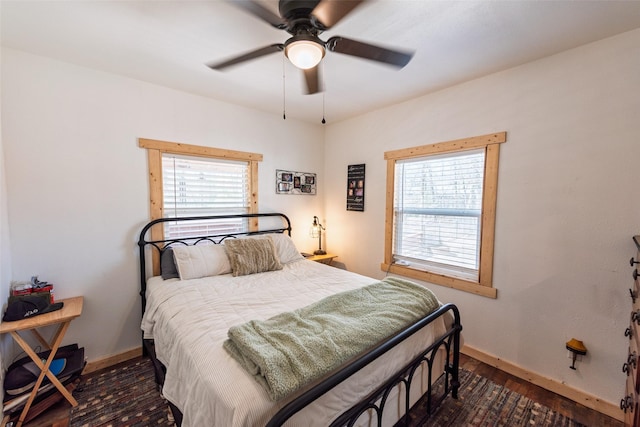 bedroom featuring baseboards, multiple windows, wood finished floors, and a ceiling fan
